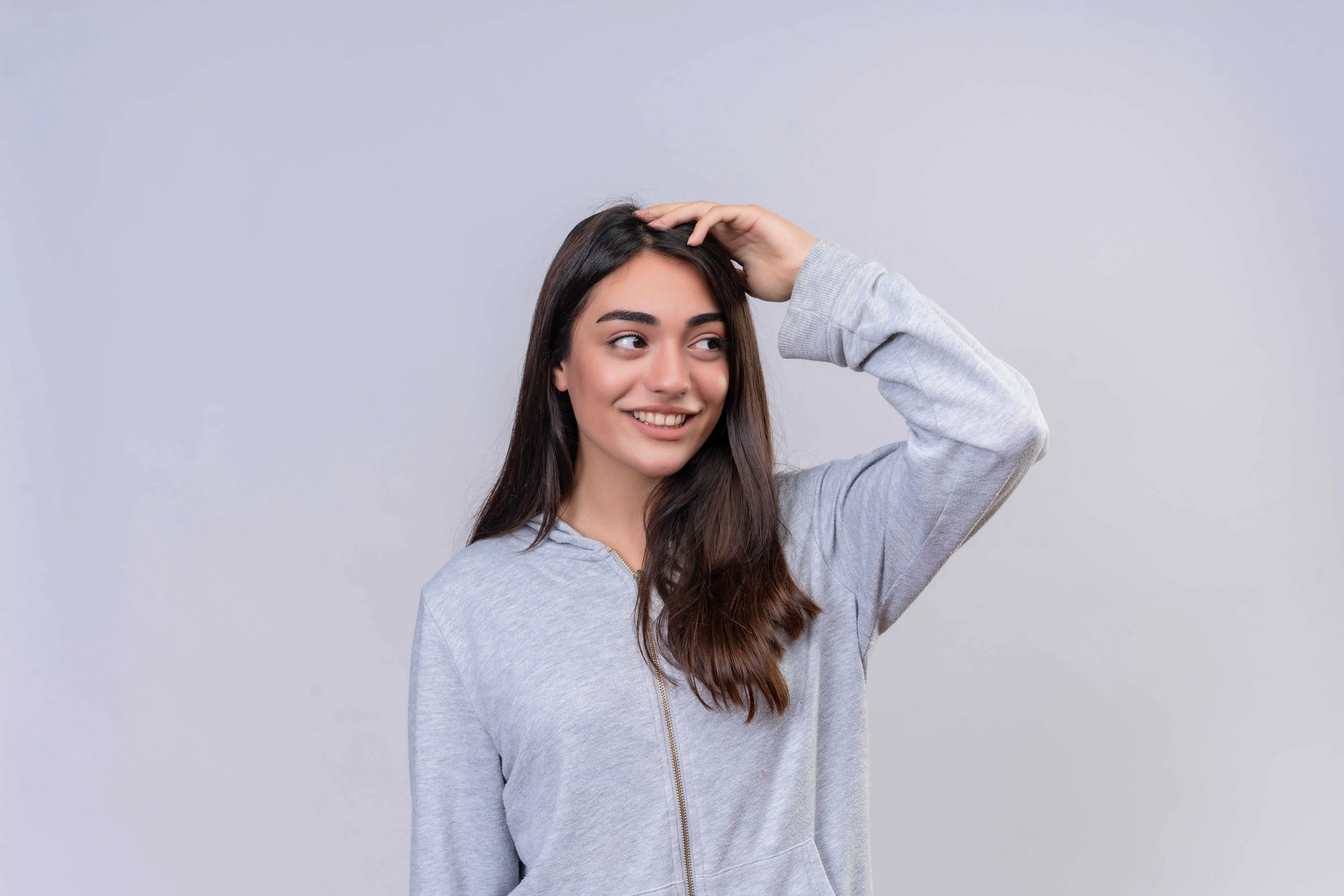 a girl standing in a grey hoodie with great hair.